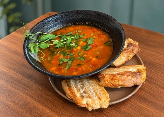 Marokkansk suppe med kikerter og kylling i en svart skål, toppet med urter og servert med ristet brød