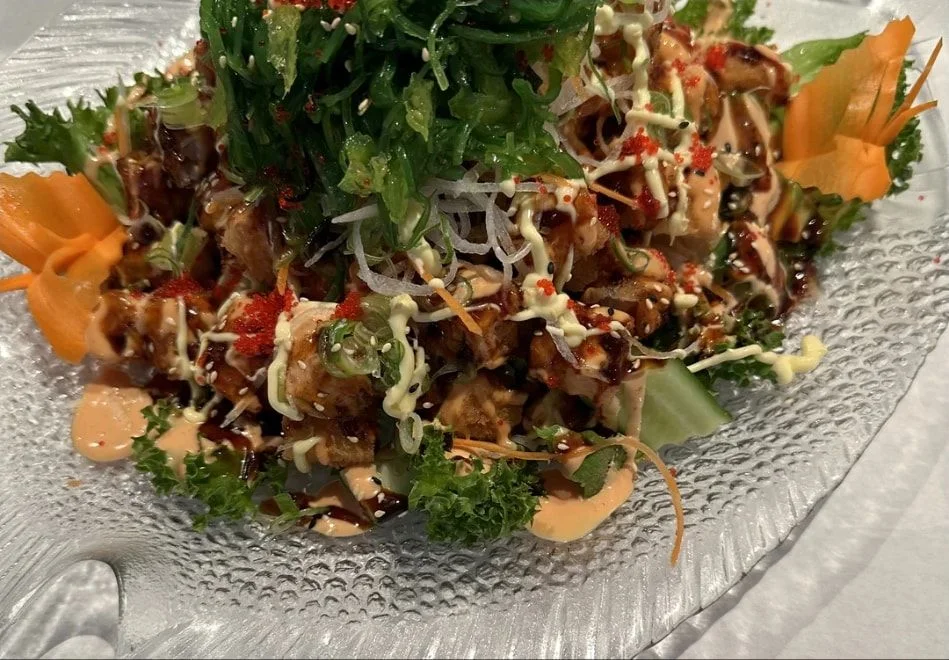 Tempurasalat med tang, sesamfrø, rogn og saus på et glassfat