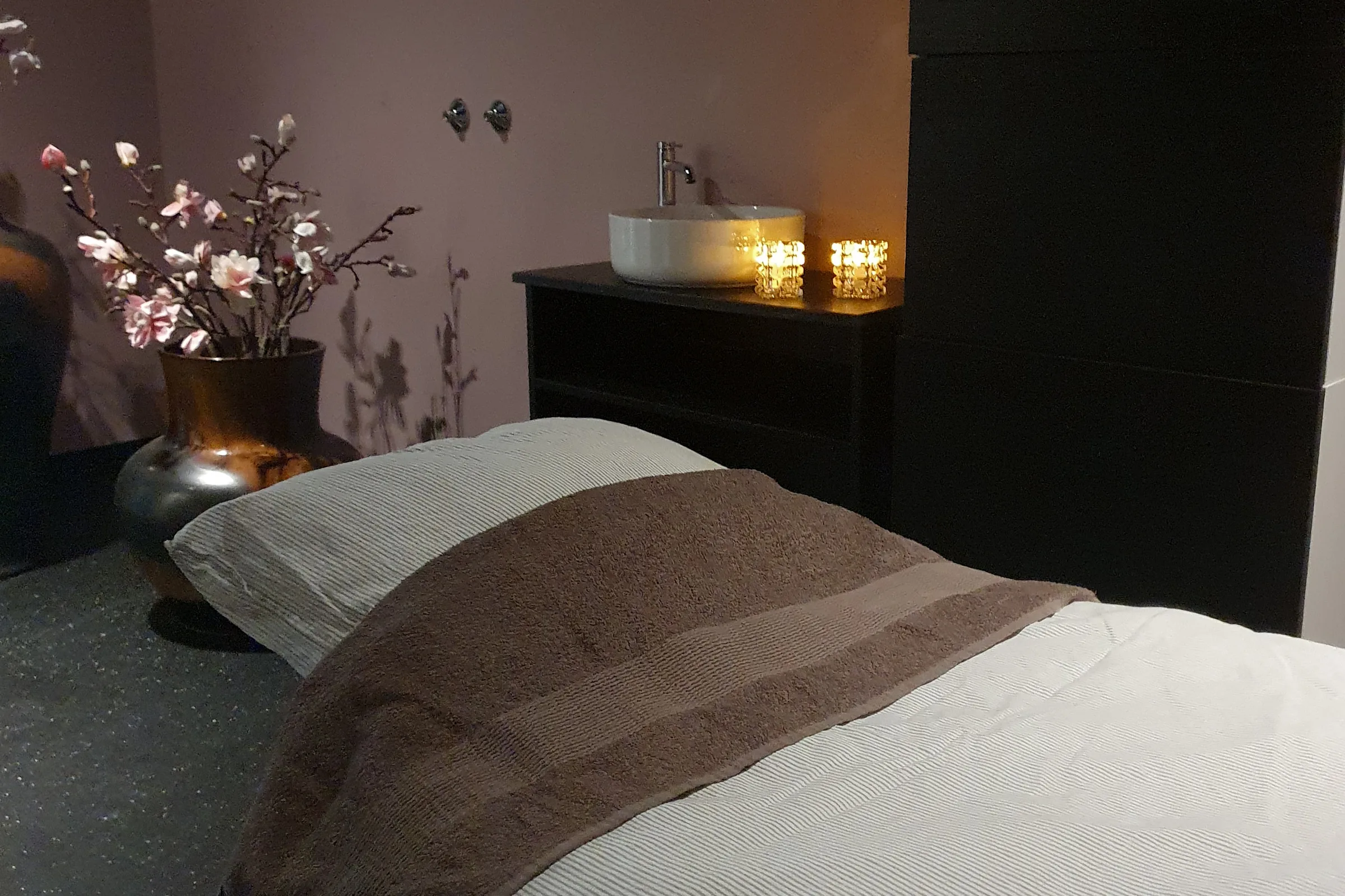 Behandlingsrom hos Sparkling Spa i Heggedal med massasjebenk, levende lys og blomster